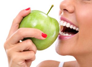 Woman about to bite into a green apple