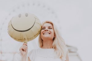 Blonde attractive woman smiling with a smiley face balloon