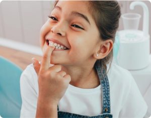Kid pointing at top teeth smiling