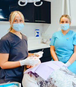 Close up of Jenny the practice manager with a dental nurse, looking at a patient in the clinic